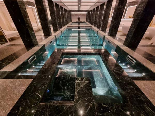 Une piscine d'intérieur en marbre et son éclairage diffus