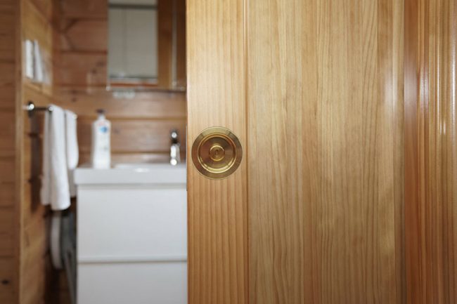 Poignée rosace à condamnation Maison ORSTEEL installée sur une porte coulissante en bois.